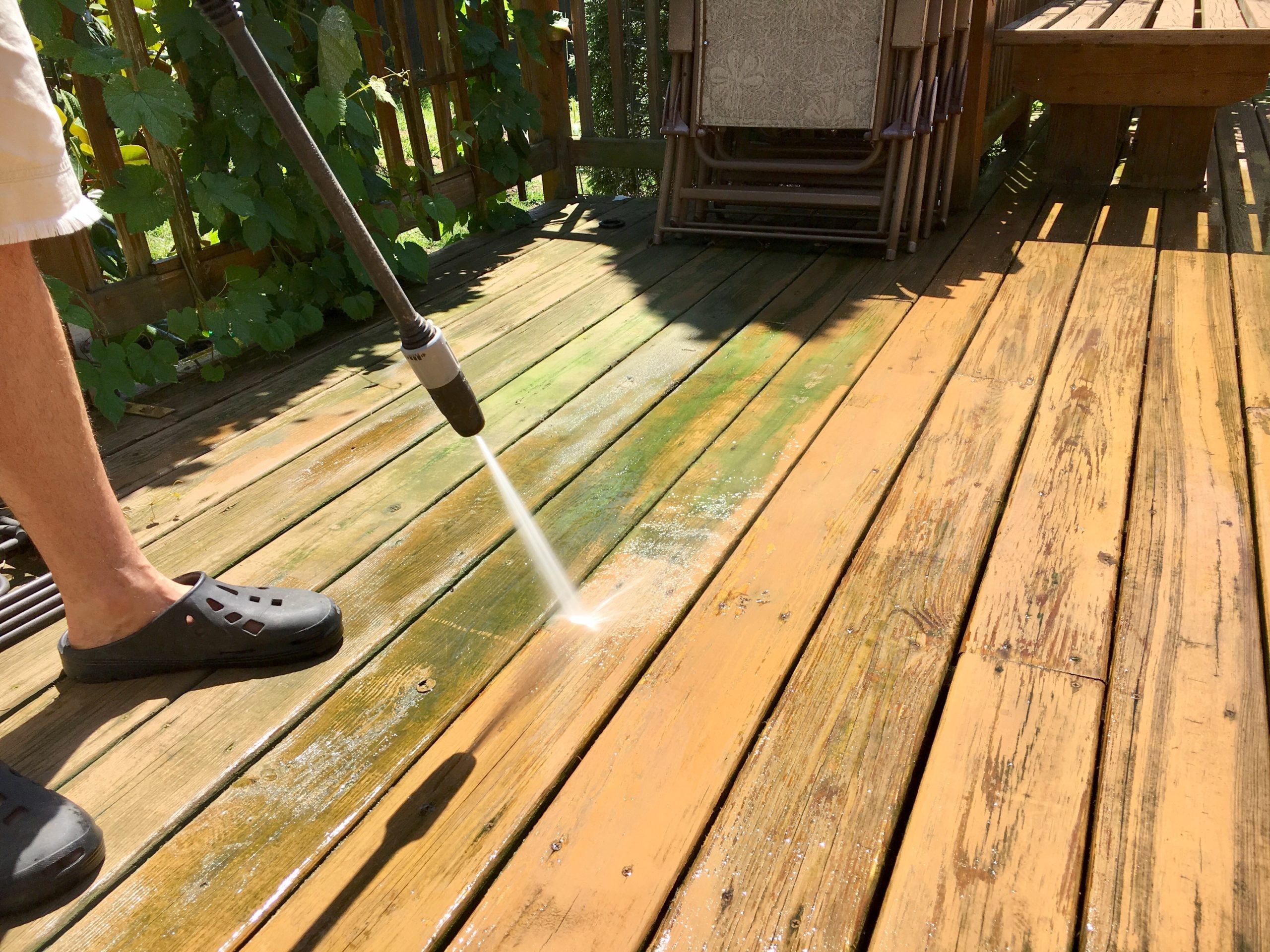 Homeowner power washing deck in the summertime.